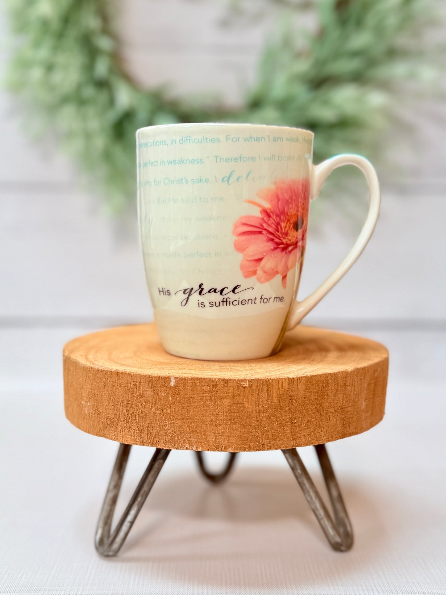 His Grace Is Sufficient scripture coffee mug with faith-based design styled on a wooden stool with greenery background