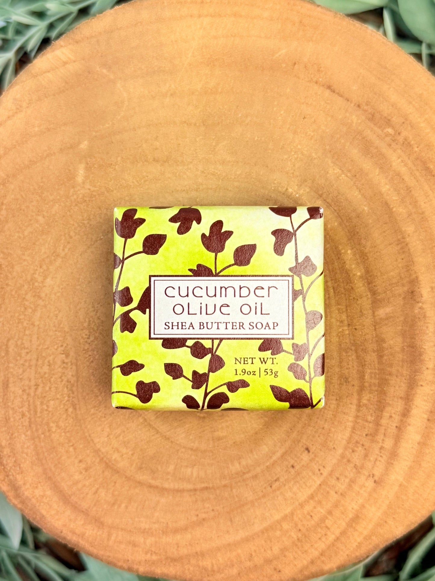 Bar of cucumber olive oil soap with a decorative label on a wooden surface
