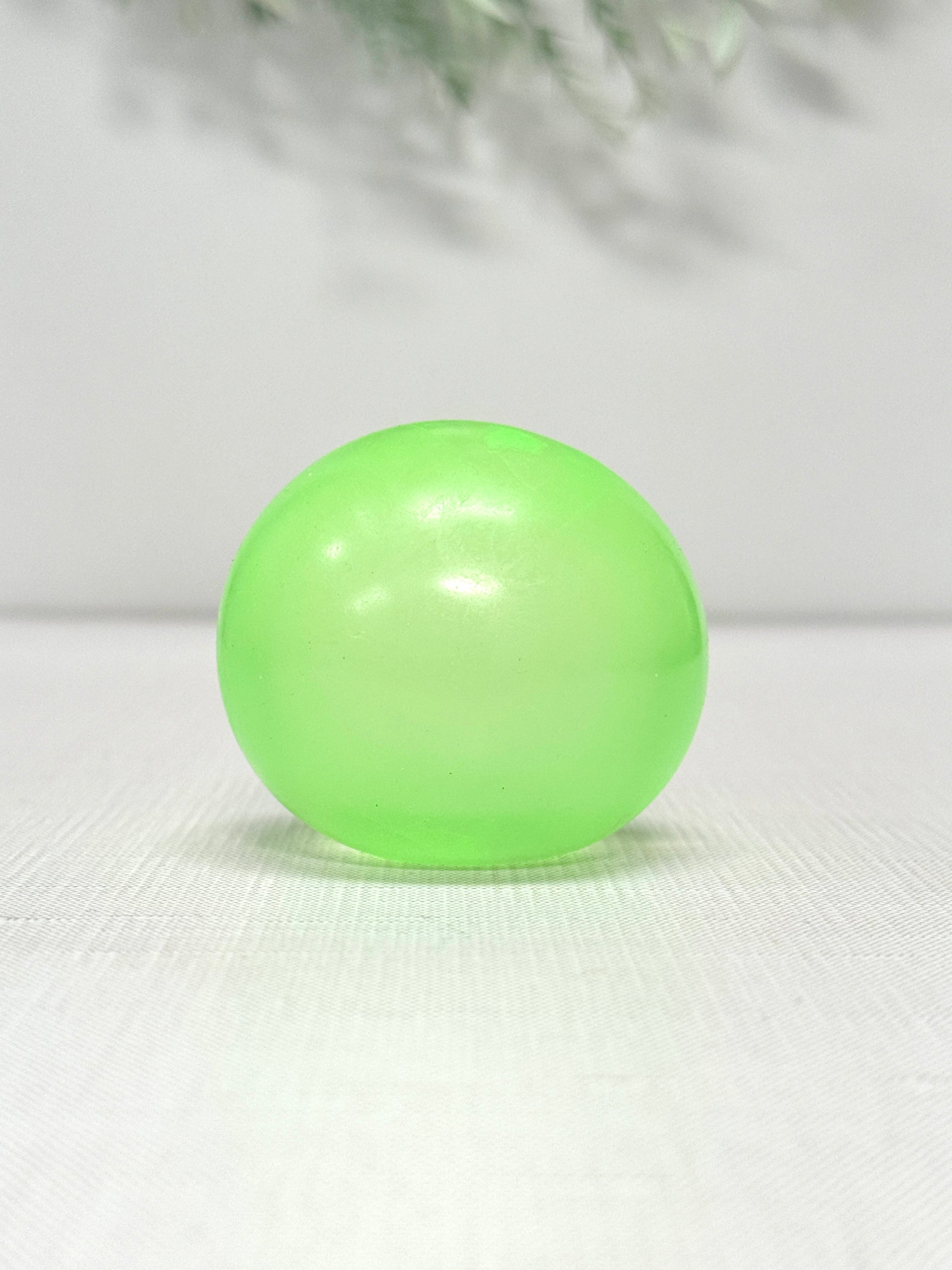 Glow in the dark gummy squish ball sensory toy available in green, blue, and yellow
