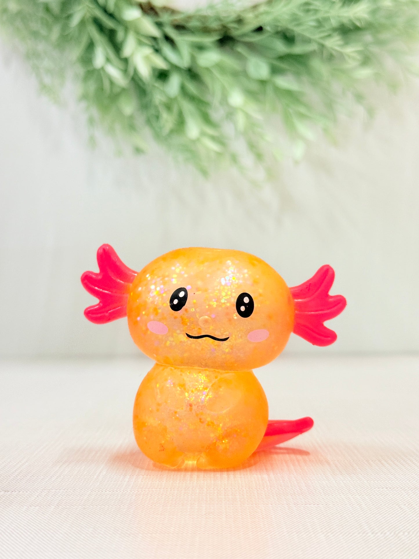 Glittery axolotl squish toy in orange sensory fidget