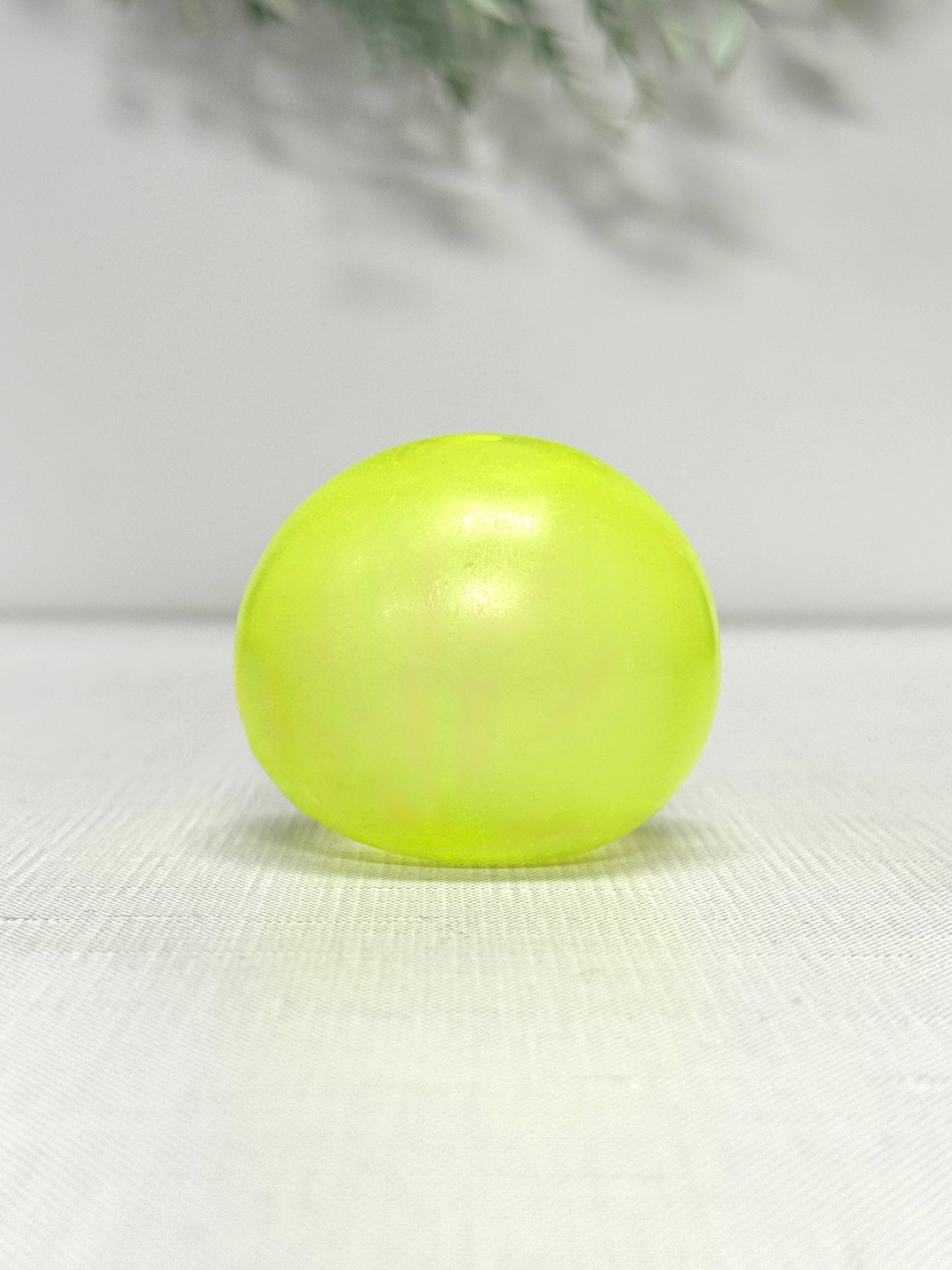 Glow in the dark gummy squish ball sensory toy available in green, blue, and yellow